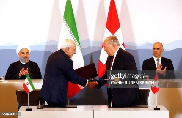 Iranian President Hassan Rouhani and Swiss President Alain Berset clap as Iranian Foreign Minister Mohammad Javad Zarif and Swiss Economic Minister...