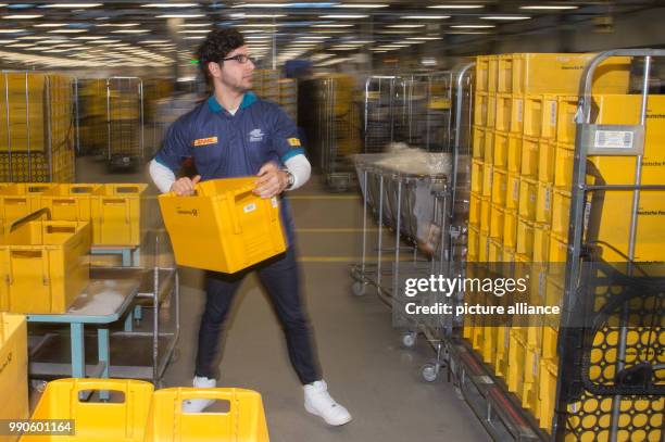 February 2018, Germany, Osterweddingen: Anas Almalla who fled from Damascus, Syria, works at the mail centre of the Deutsche Post and pile up boxes....
