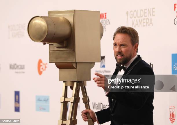 Dpatop - 22 February 2018, Germany, Hamburg, Golden Camera Awards Ceremony: Moderator Steven Gaetjen poses next to a fake camera. Photo: Georg...