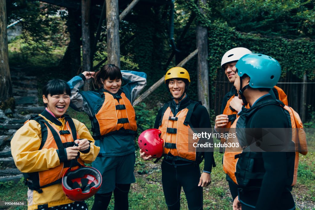 Groep van mannen en vrouwen het dragen van reddingsvesten en helmen voordat een rivier rafting tour