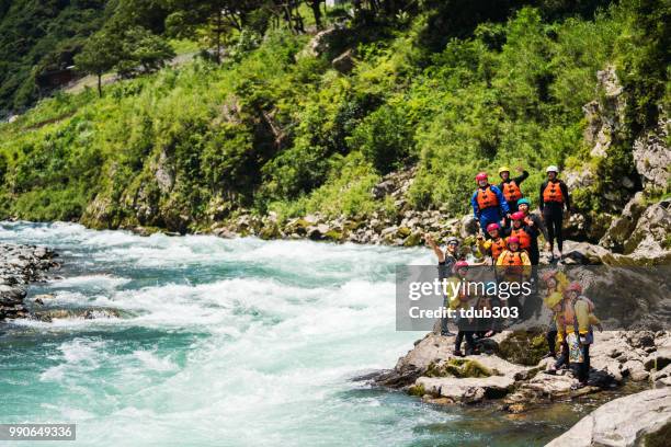 Large group of men and women exploring a riverbank while white water river rafting