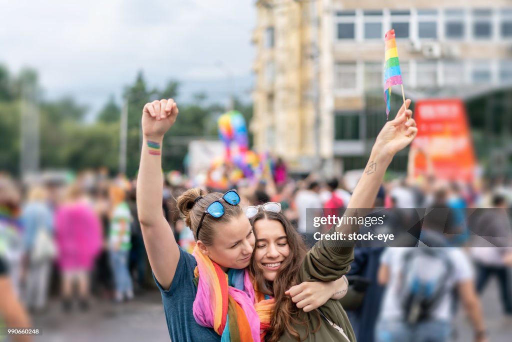 Beautiful female couple hugging while marching on the street