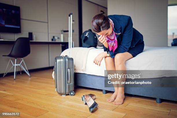 burnout cabin crew member is standing alone in her hotel room after flight - air stewardess stock pictures, royalty-free photos & images
