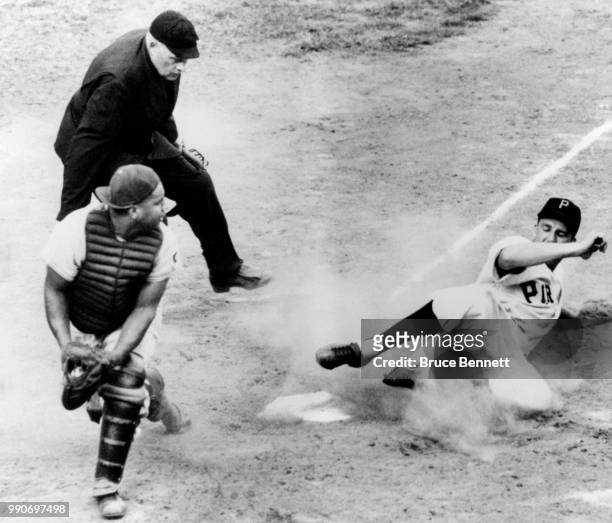 Ralph Kiner of the Pittsburgh Pirates slides safely into home as catcher Roy Campanella of the Brooklyn Dodgers is pulled off the plate as umpire...