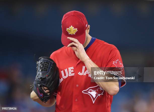 Happ of the Toronto Blue Jays adjusts his cap as the team wears red jerseys on Canada Day during MLB game action against the Detroit Tigers at Rogers...