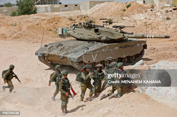 Israeli soldiers from the Kfir brigade's Shimshon battalion regroup by a Merkava battle tank during a military exercise at the Tzeelim army base on...