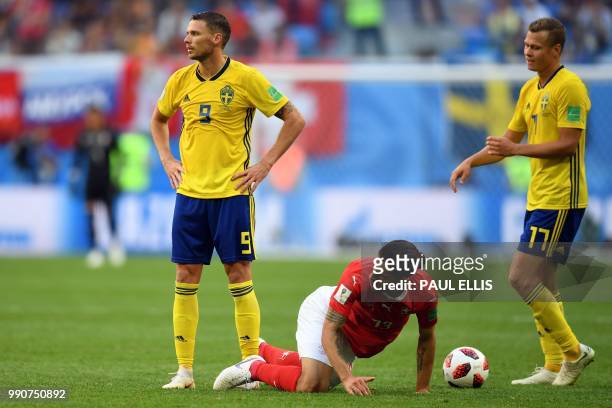Switzerland's defender Ricardo Rodriguez kneels on the ground past Switzerland's forward Haris Seferovic and Sweden's midfielder Viktor Claesson...