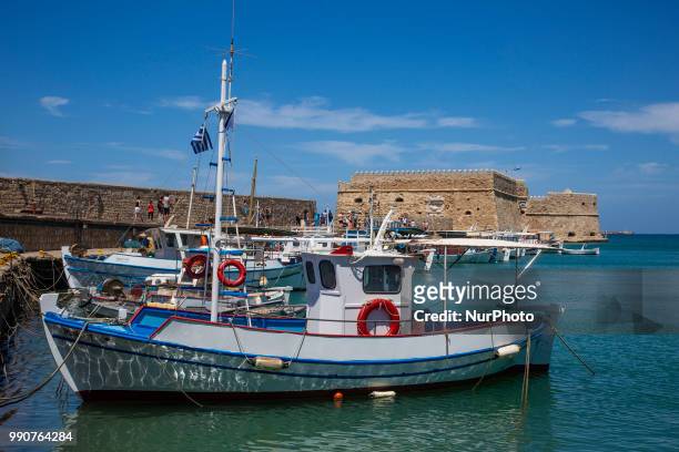 Little port in Heraklion city. Traditional fishing boats moored in the harbour with the Venetian Koules castle in the background. Heraklion, Crete...