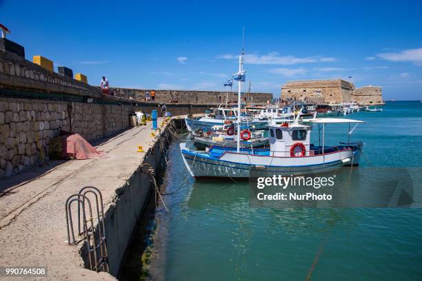 Little port in Heraklion city. Traditional fishing boats moored in the harbour with the Venetian Koules castle in the background. Heraklion, Crete...