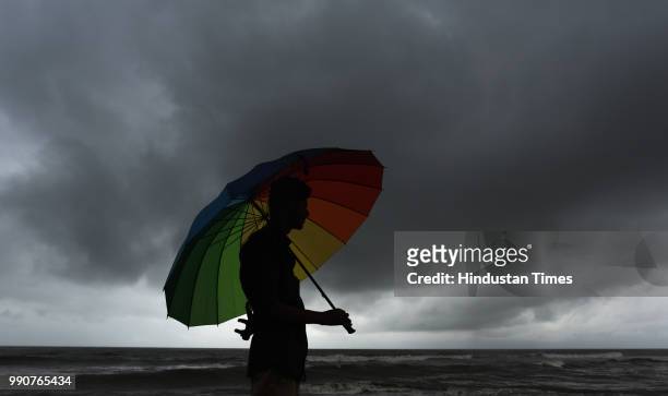 Man holding umbrella as dark clouds hover on Mumbai skyline at Bandstand on July 2, 2018 in Mumbai, India.
