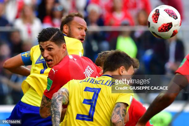 Sweden's defender Andreas Granqvist and defender Victor Lindelof jump to head the ball with Switzerland's midfielder Steven Zuber during the Russia...
