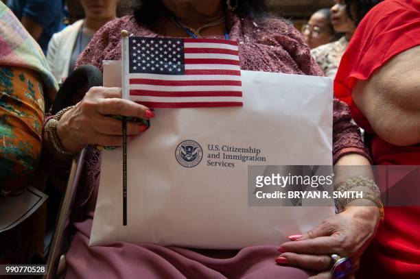 Woman holds the flag and her paperwork as the US Citizenship and Immigration Services welcomes 200 new citizens from 50 countries during a ceremony...