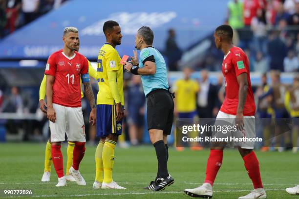 Referee Damir Skomina gets a red card out, ready to book Michael Lang of Switzerland, as he speaks to Isaac Kiese Thelin of Sweden during the 2018...