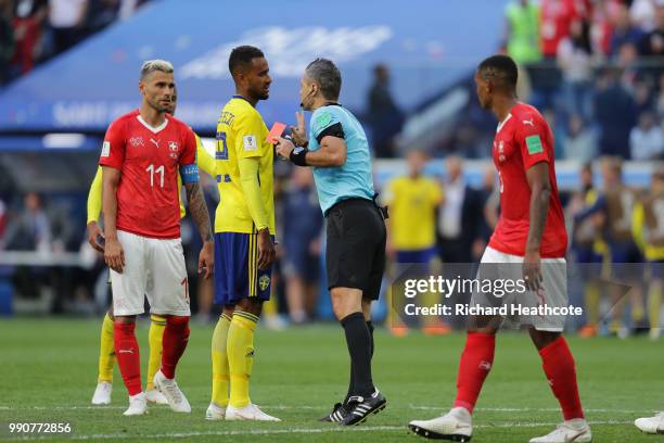 Referee Damir Skomina discusses with Valon Behrami of Switzerland and Isaac Kiese Thelin of Sweden after giving a red card to Michael Lang of...