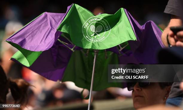 Spectator shelters from the sun beneath an umbrella as Belarus' Aliaksandra Sasnovich returns against Czech Republic's Petra Kvitova during their...