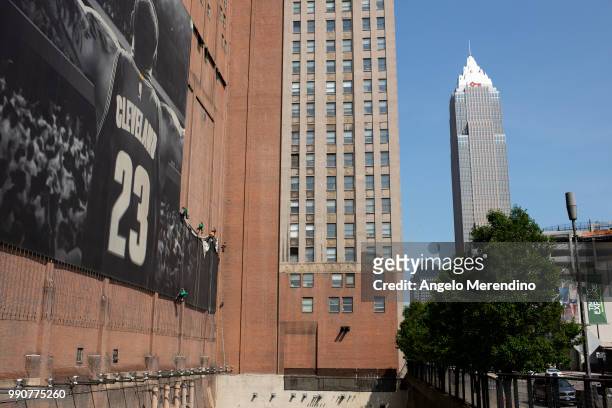 Workers take down the LeBron James banner from the Sherwin Williams building on the corner of Ontario and West Huron on July 3, 2018 in Cleveland,...