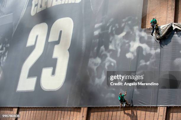 Workers take down the LeBron James banner from the Sherwin Williams building on the corner of Ontario and West Huron on July 3, 2018 in Cleveland,...