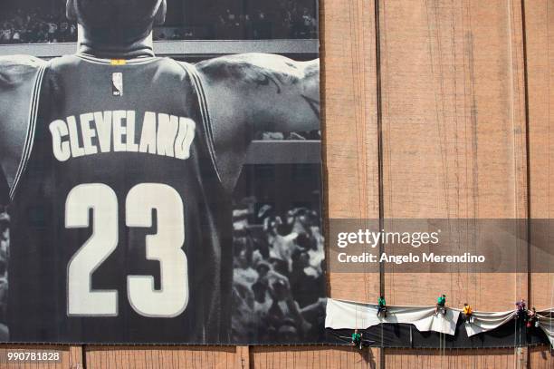 Workers take down the LeBron James banner from the Sherwin Williams building on the corner of Ontario and West Huron on July 3, 2018 in Cleveland,...