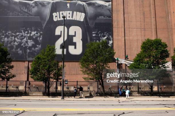 Workers take down the LeBron James banner from the Sherwin Williams building on the corner of Ontario and West Huron on July 3, 2018 in Cleveland,...