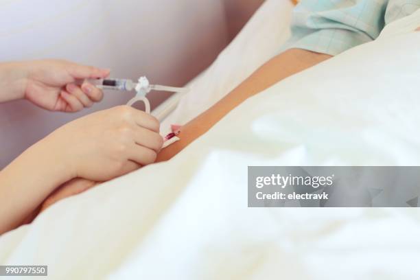 nurse using needle on patient - surgical needle stock pictures, royalty-free photos & images