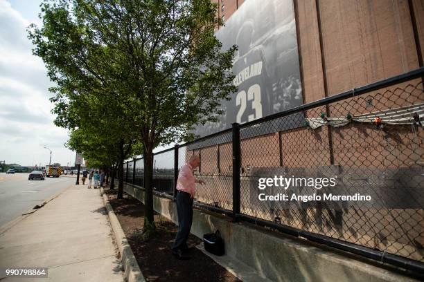 Man watches as workers remove the LeBron James banner from the Sherwin Williams building on the corner of Ontario and West Huron on July 3, 2018 in...