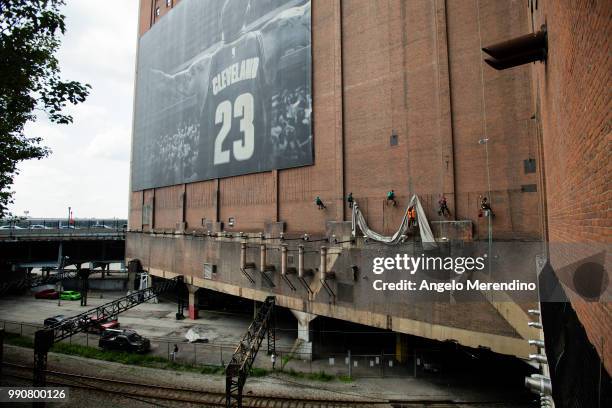 Workers take down the LeBron James banner from the Sherwin Williams building on the corner of Ontario and West Huron on July 3, 2018 in Cleveland,...