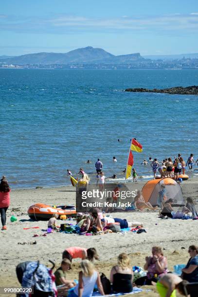 People enjoy the sun on Silver Sands beach at the start of the Scottish school holidays as the heatwave continues, with Edinburgh in the background...