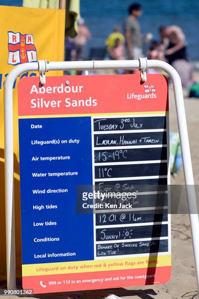 An RNLI lifeguard information board on Silver Sands beach as people enjoy the sun at the start of the Scottish school holidays as the heatwave...