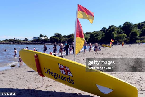 Marker flags indicate the area patrolled by RNLI lifeguards, as people enjoy the sun on Silver Sands beach at the start of the Scottish school...