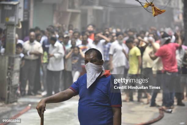 Man watches guard in the lane as a fire broke out in a building at Bazar Lane, Bhogal on July 3, 2018 in New Delhi, India.