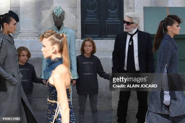German fashion designer Karl Lagerfeld , flanked by his godson Hudson Kroenig and South Sudanese-Australian model Adut Akech , acknowledges the...