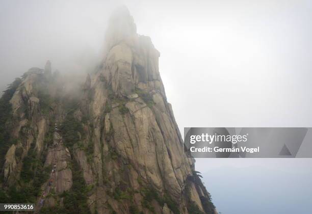 dramatic mountain peak touches the sky clouds, huangshan, china - mount olympus greek - fotografias e filmes do acervo