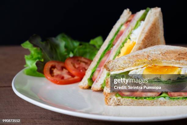 healthy breakfast sandwich with fried eggs, toasts, ham and vegetable on the white plate on wooden background. - alimentos cocinados fotografías e imágenes de stock