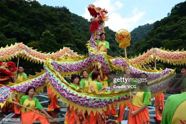 Folk artists perform dragon dance on a glass-bottomed bridge at the Gulongxia scenic spot on July 1, 2018 in Qingyuan, Guangdong Province of China. A...