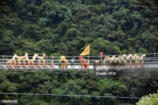 Folk artists perform dragon dance on a glass-bottomed bridge at the Gulongxia scenic spot on July 1, 2018 in Qingyuan, Guangdong Province of China. A...