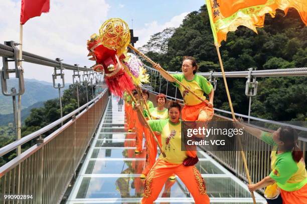 Folk artists perform dragon dance on a glass-bottomed bridge at the Gulongxia scenic spot on July 1, 2018 in Qingyuan, Guangdong Province of China. A...