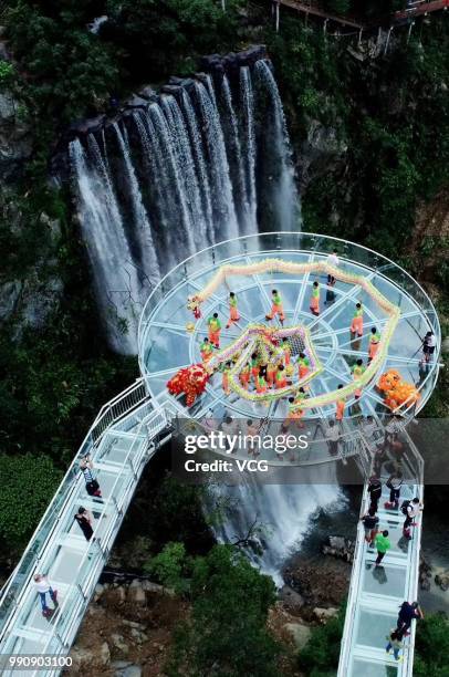 Folk artists perform dragon dance on a glass-bottomed bridge at the Gulongxia scenic spot on July 1, 2018 in Qingyuan, Guangdong Province of China. A...