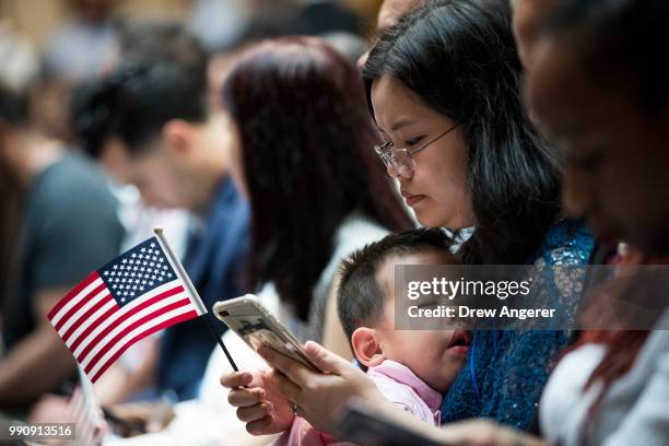 An immigrant woman holds a child before becoming a U.S. Citizen during a naturalization ceremony at the New York Public Library, July 3, 2018 in New...