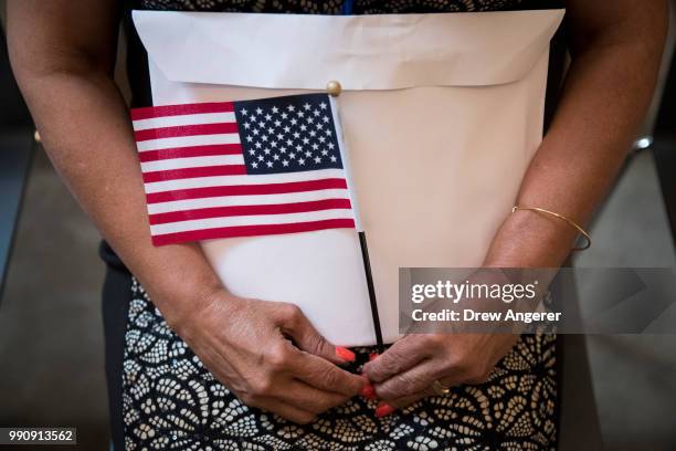 Woman holds an flag and her citizenship packet during a naturalization ceremony at the New York Public Library, July 3, 2018 in New York City. 200...