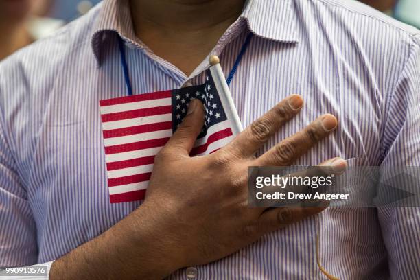 New U.S. Citizen holds a flag to his chest during the Pledge of Allegiance during a naturalization ceremony at the New York Public Library, July 3,...