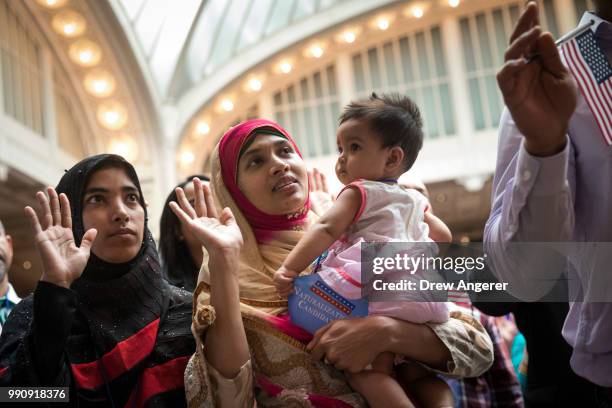 New U.S. Citizen Mosammat Rasheda Akter, orginally Bangladesh, holds her 7 month-old daughter Fahmida as she recites the Oath of Allegiance during...