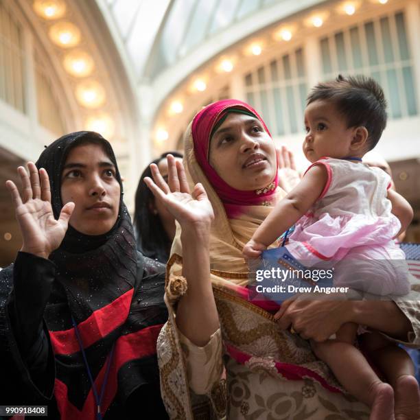 New U.S. Citizen Mosammat Rasheda Akter, orginally Bangladesh, holds her 7 month-old daughter Fahmida as she recites the Oath of Allegiance during...