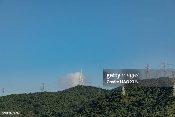 numbers of high voltage towers along the mountain in a sunny day - liao xun stock-fotos und bilder