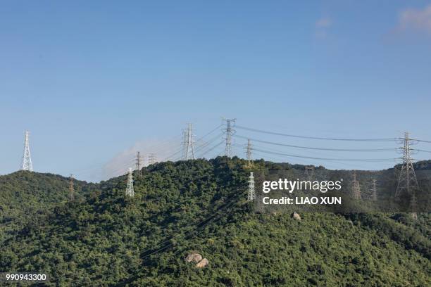 numbers of high voltage towers along the mountain in a sunny day - liao xun stock-fotos und bilder