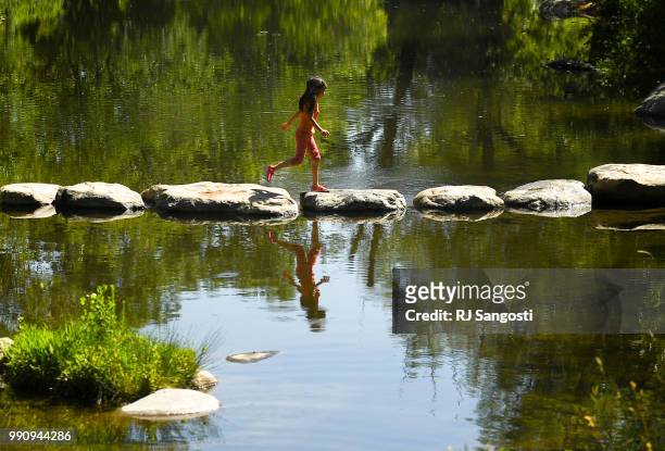 Amelia Tai of Boulder, crosses a rock path near the Boulder Creek path on July 3, 2018 in Boulder, Colorado. Weather in the area was in the low 90s.