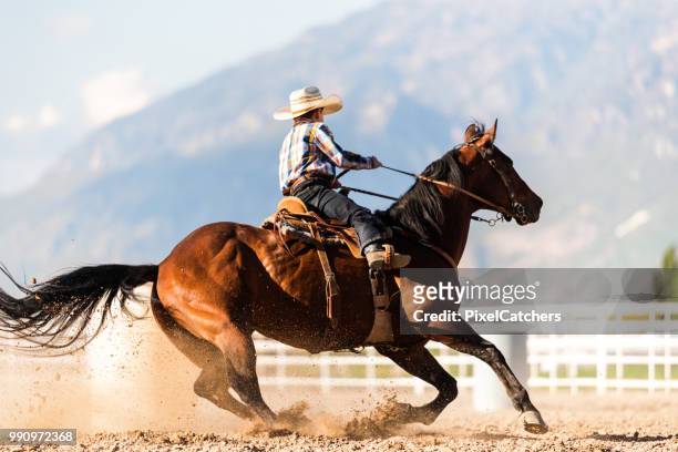 young boy practices barrel racing in a paddock on ranch - faster horses stock pictures, royalty-free photos & images