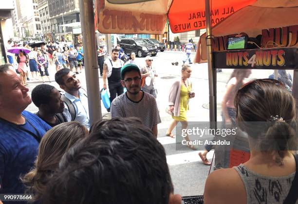 Pedestrians watch the penalty shooting of the 2018 FIFA World Cup Russia Round of 16 match between Colombia and England, from the nuts seller's...