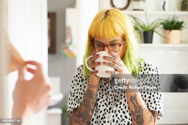 young hipster woman drinking from a mug in her kitchen - coffee drink photos et images de collection
