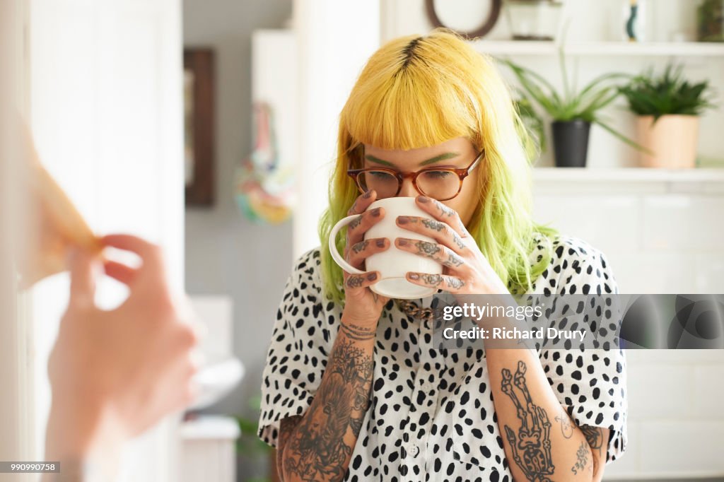 Young hipster woman drinking from a mug in her kitchen