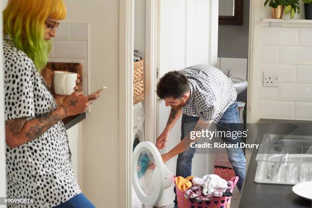 young hipster couple doing their laundry - rolwisseling stockfoto's en -beelden